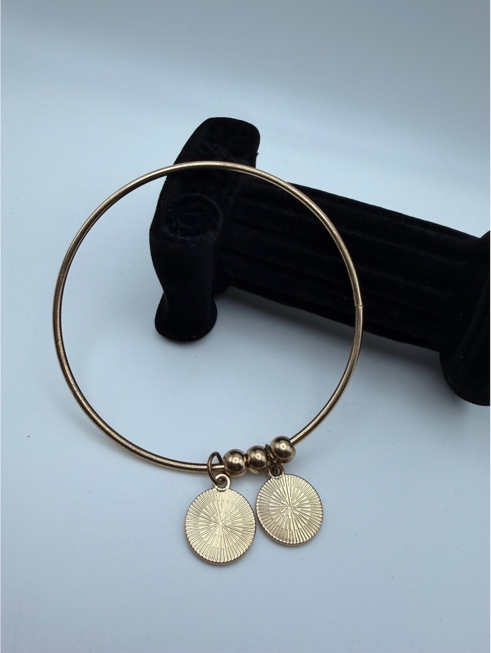 Gold tone bangle with two disc charms